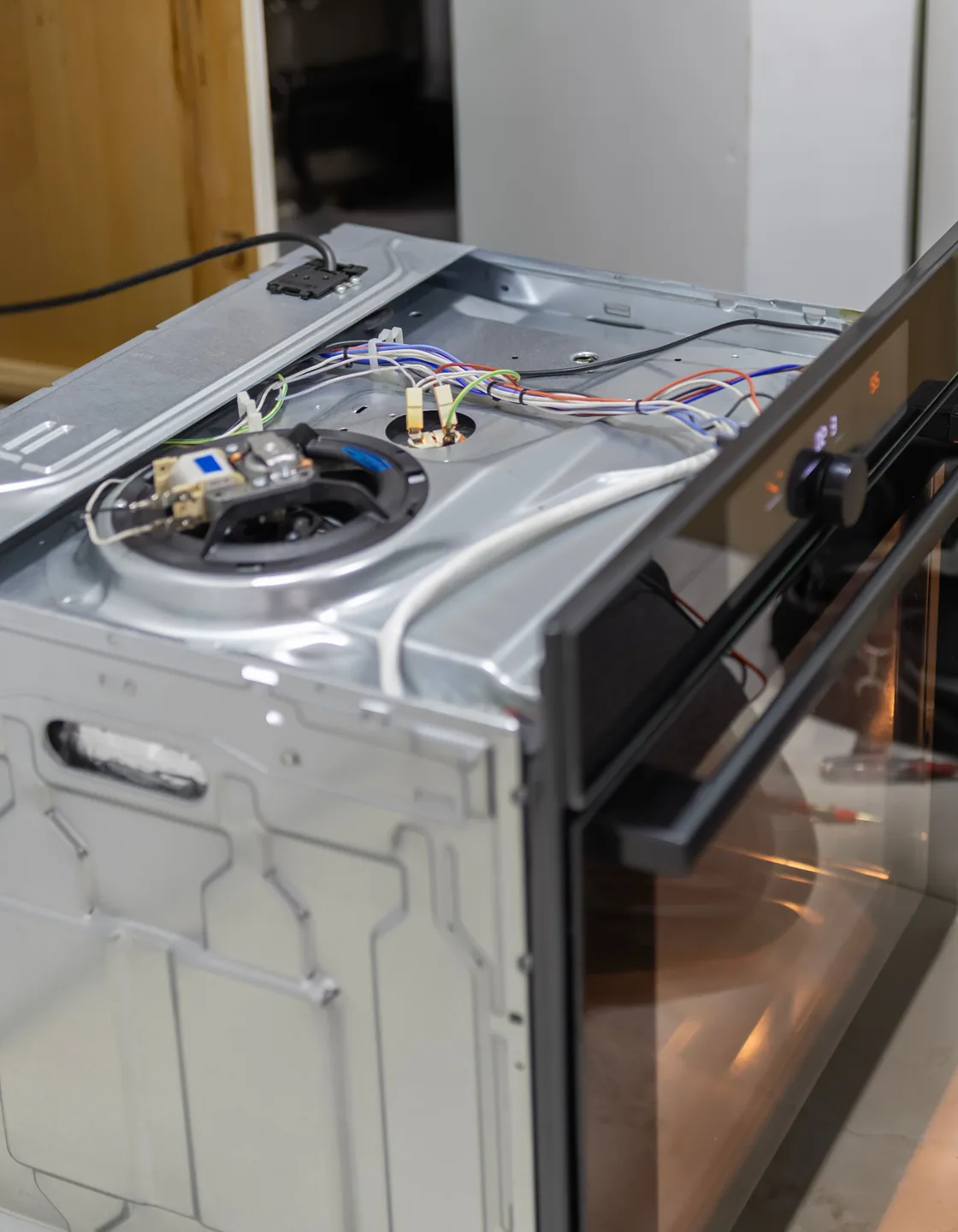 Geöffneter Einbaubackofen mit freiliegendem Heißluftmotor und Verkabelung bei der Reparatur