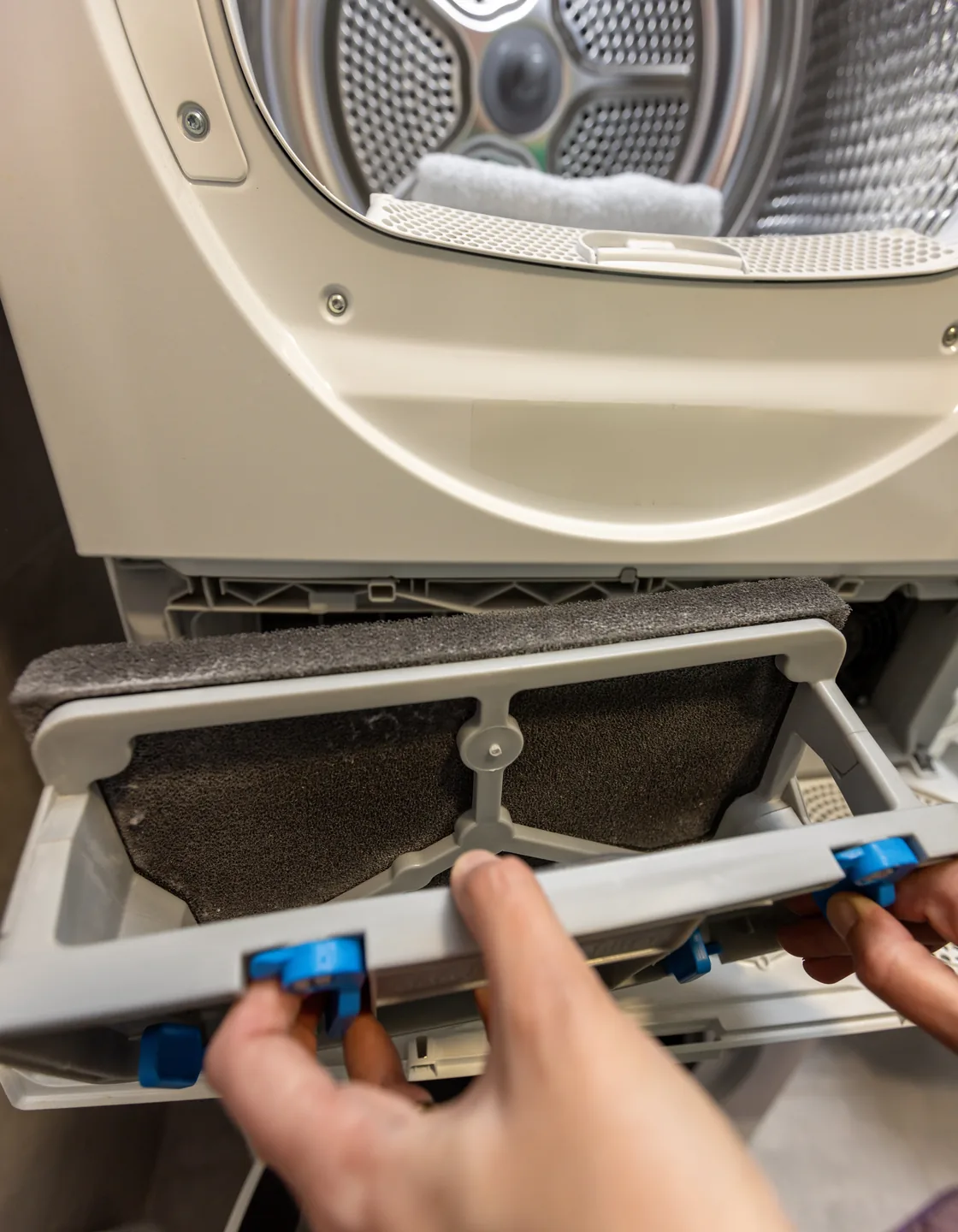 Stark mit Flusen zugesetztes Flusensieb wird aus einem Wäschetrockner gezogen