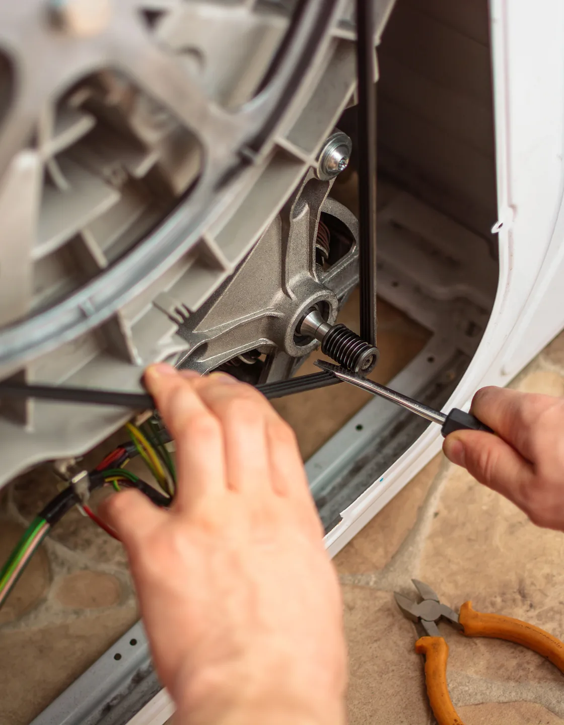 Geöffnete Rückseite einer Waschmaschine mit Antriebsriemen und Riemenscheibe bei der Reparatur